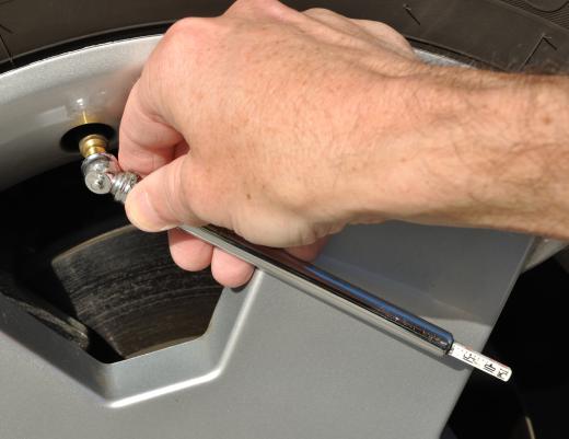 A person checking tire pressure by hand. Tire pressure monitoring systems do this automatically.